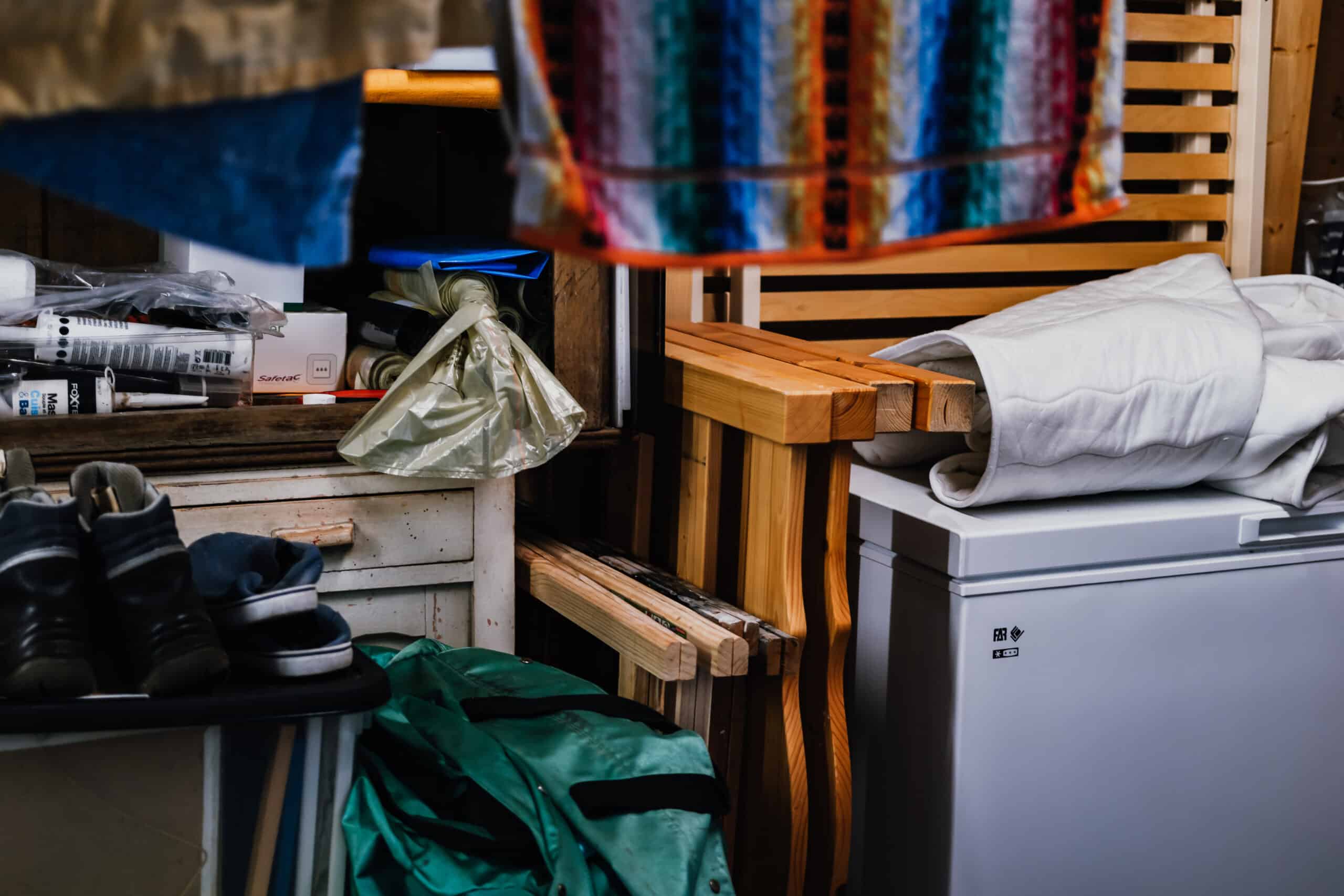 Cartons Déménagement Salon Ancien Lumière Naturelle Gros cartons de déménagement scellés au premier plan dans une pièce peu éclairée avec fenêtre et un canapé bleu et jaune visible au fond.